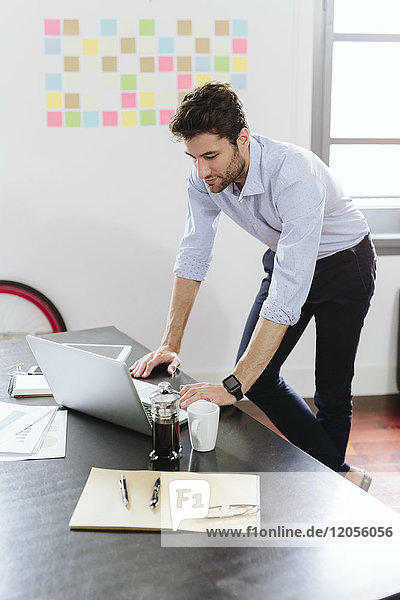 Young businessman working in office using laptop