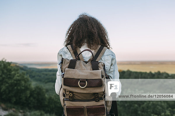 Back view of teenage girl with backpack in nature