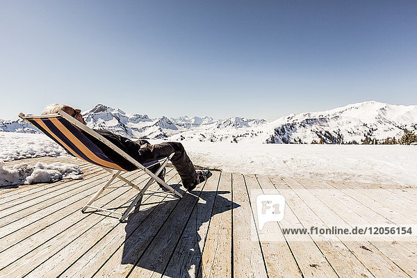 Österreich  Damuels  Senior im Liegestuhl auf dem Sonnendeck in der Winterlandschaft