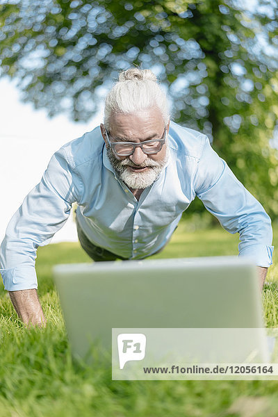 Erwachsener Mann mit Laptop-Training im Park