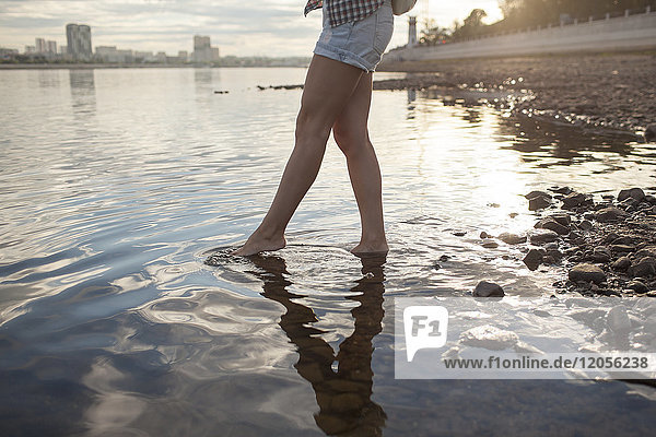 Woman wading in a river at sunset