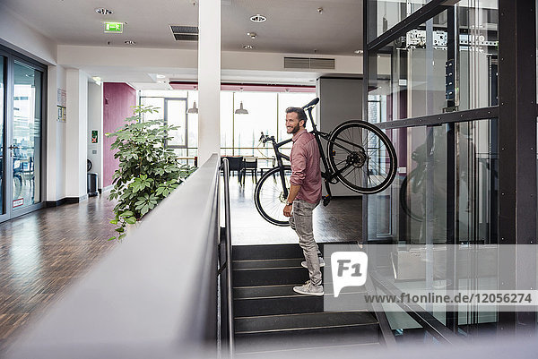 Mann mit Fahrrad oben im modernen Büro