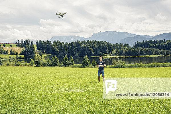 Germany  Bavaria  Pfronten  young man flying his drone at lakeside