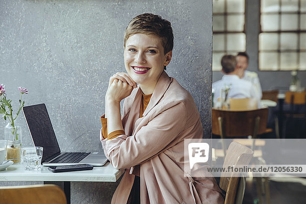 Porträt einer lächelnden Frau im Café mit Laptop