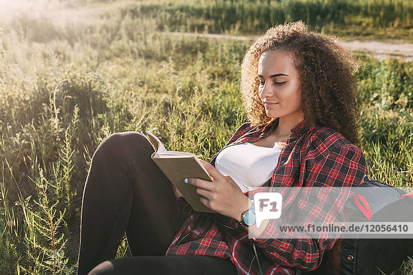 Teenage girl reading book on a meadow