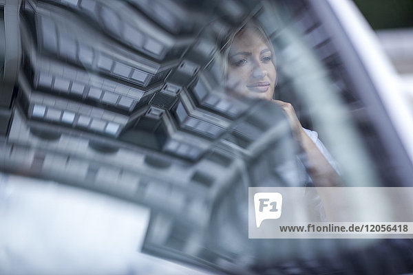 Businesswoman in car with reflection of urban building