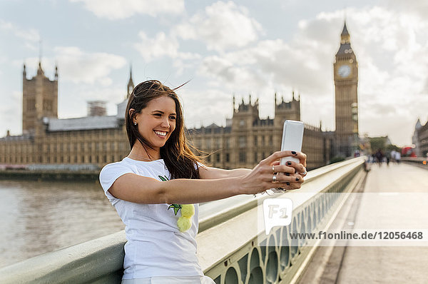 UK,  London,  schöne Frau,  die einen Selfie auf der Westminster Bridge nimmt.