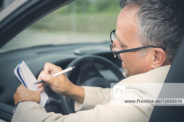 Businessman sitting in his car making notes