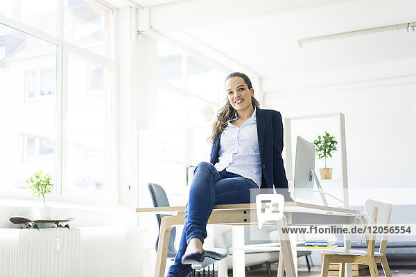 Portrait of smiling businesswoman sitting on table in a loft