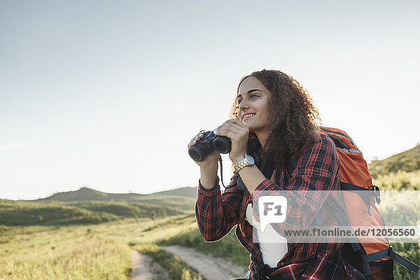 Teenage girl with backpack and binoculars in nature