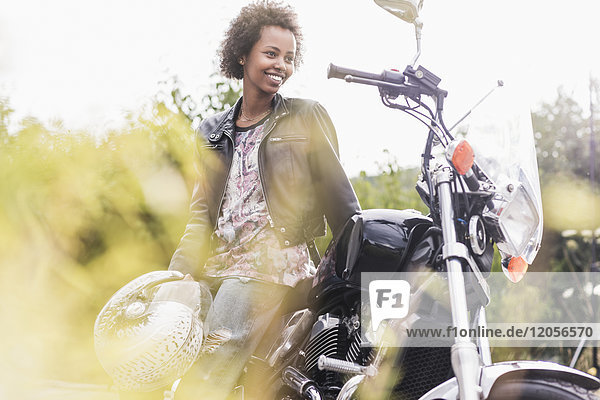 Lächelnde junge Frau mit ihrem Motorrad