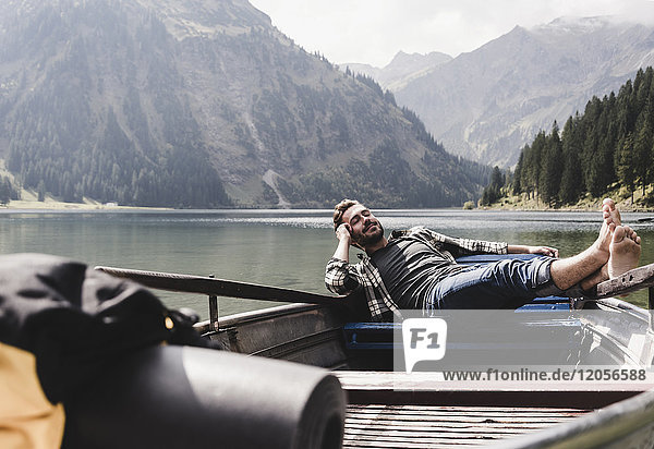 Österreich,  Tirol,  Alpen,  entspannter Mann im Boot auf dem Bergsee