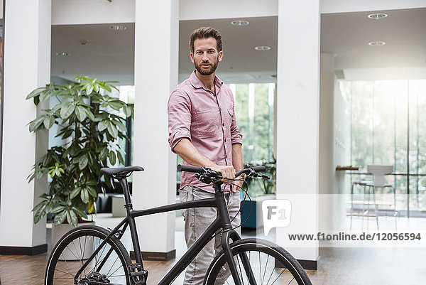 Portrait of man with bicycle in office
