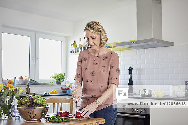 Reife Frau bei der Zubereitung eines Salats in der Küche
