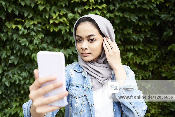Junge Frau mit Hijab auf dem Handy-Bildschirm