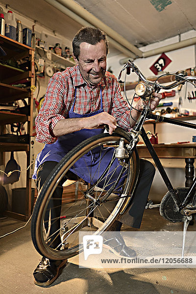 Älterer Mann repariert Fahrrad in seiner Werkstatt