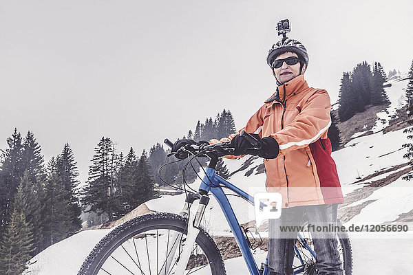 Austria  Damuels  woman with mountain bike and action cam in winter landscape