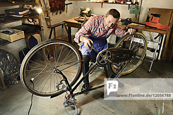 Senior man checking bicycle in his workshop