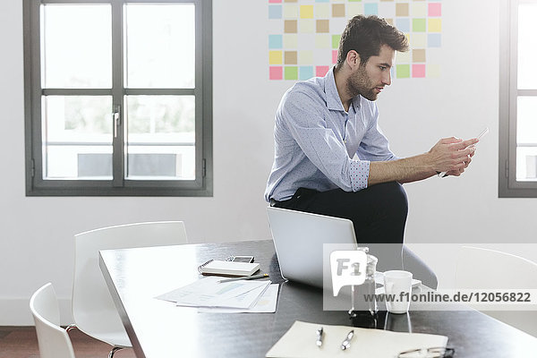 Young businessman working in office using smartphone