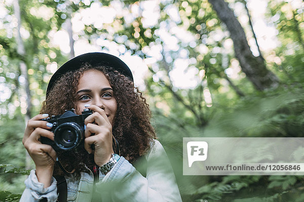 Portrait of smiling teenage girl taking pictures in nature