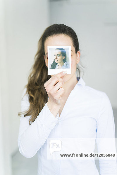 Woman covering her face with instant photo of herself