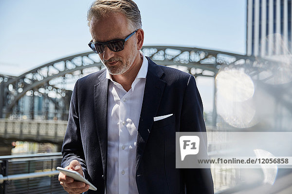 Deutschland  München  Portrait eines Geschäftsmannes mit Sonnenbrille auf dem Handy
