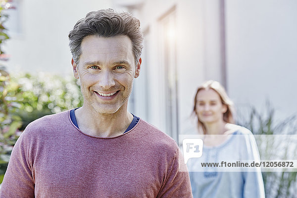 Portrait of smiling man with woman in background