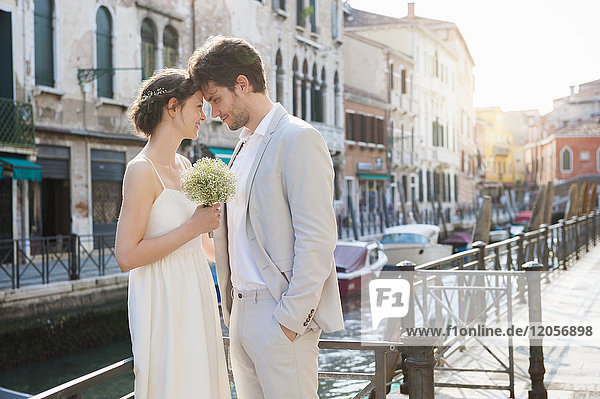 Italy  Venice  bridal couple standing head to head in front of canal