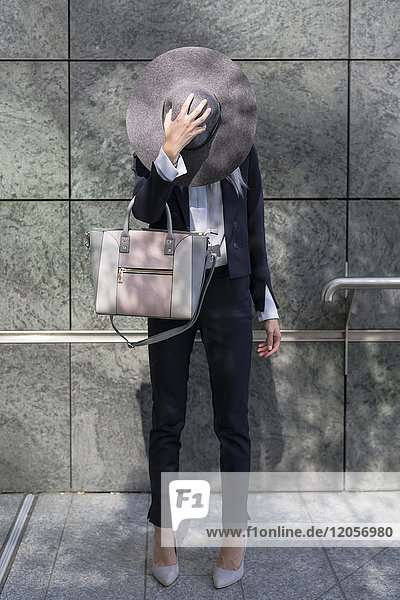 Businesswoman putting on floppy hat outdoors