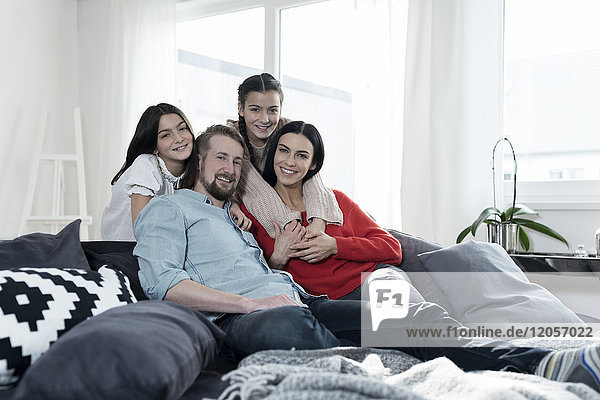 Family portrait of parents and twin daughters on sofa in living room