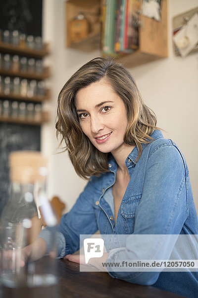 Portrait of smiling woman leaning on kitchen table