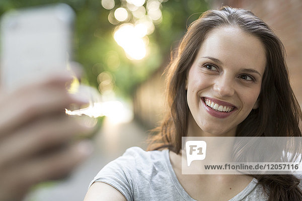 Portrait of happy young woman outdoors taking a selfie