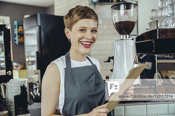 Porträt einer lachenden Kellnerin mit Menü in einem Cafe