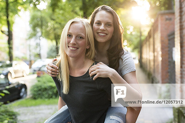 Young woman giving her friend a piggyback ride