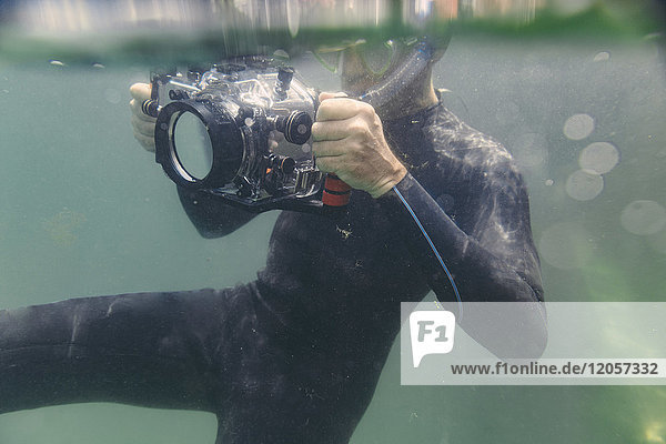 Mann taucht mit Unterwasser-DSLR-Kameragehäuse