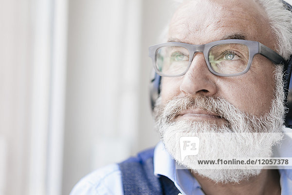 Erwachsener Mann mit Brille und Kopfhörer am Fenster