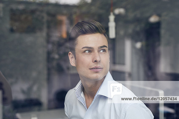 Young businessman behind glass pane in office