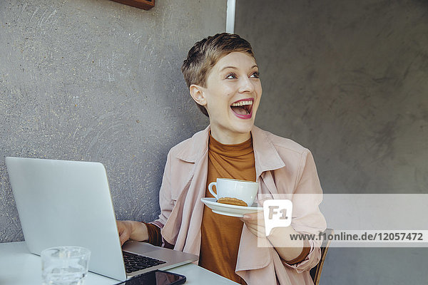 Überraschte Frau mit ihrem Laptop bei einer Tasse Kaffee im Cafe
