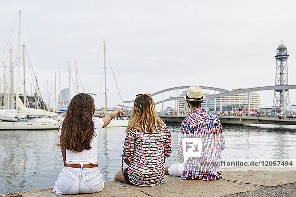 Spain  Barcelona  three tourists sitting on a pier in the city