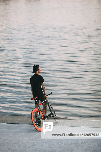 Junger Mann mit Fixie Bike am Wasser
