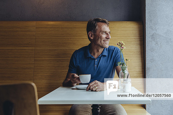 Lächelnder reifer Mann sitzt im Cafe