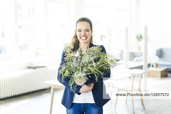 Portrait of happy businesswoman holding flowerpot