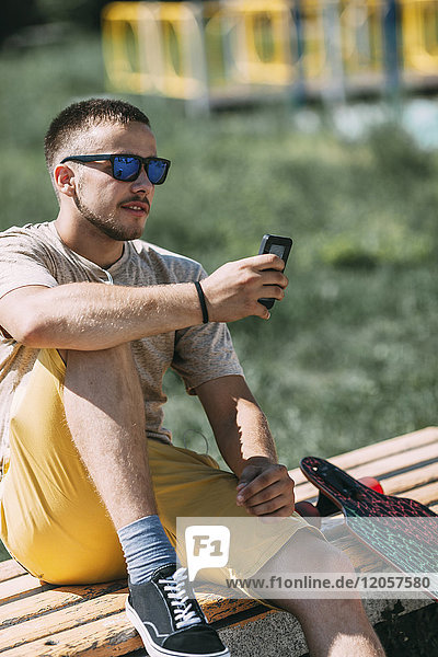 Young man sitting on a bench using cell phone