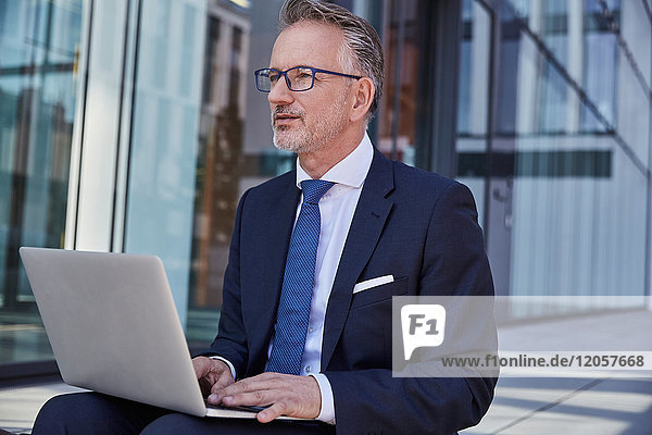 Portrait of businessman using laptop outdoors
