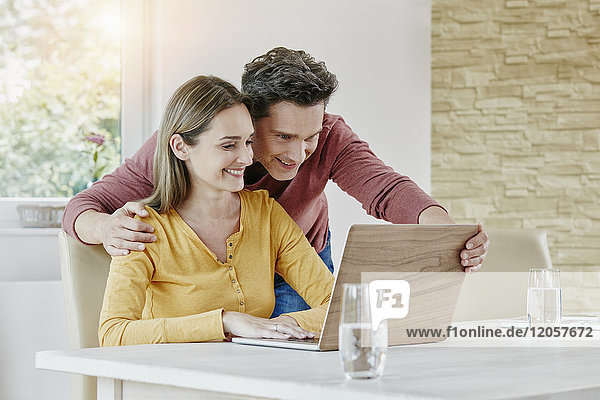 Happy couple at home using laptop