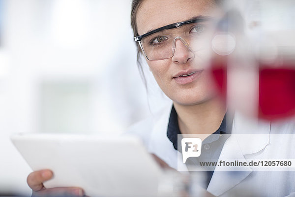 Wissenschaftler der im Labor arbeitet und eine Tablette in der Hand hält.