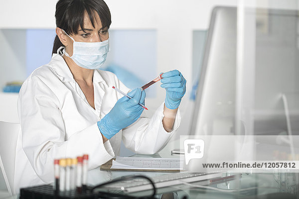 Frau untersucht Reagenzglas mit Flüssigkeit im Labor