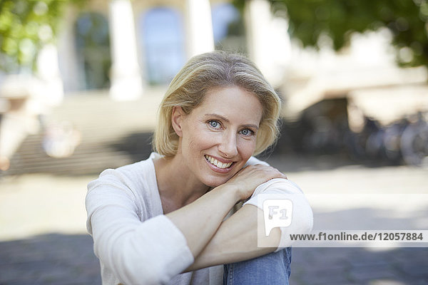 Porträt einer lächelnden blonden Frau mit verschränkten Armen