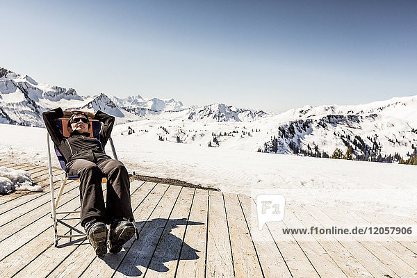 Österreich  Damuels  Frau entspannt im Liegestuhl auf dem Sonnendeck in Winterlandschaft