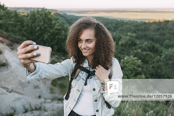 Smiling teenage girl taking selfie in nature